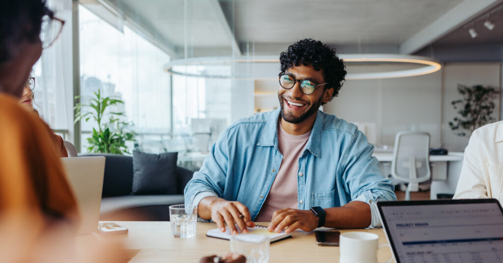 Young professional talking at conference table with other colleagues