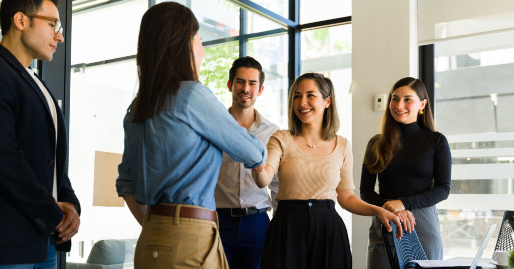 Colleagues shaking hands in front of team