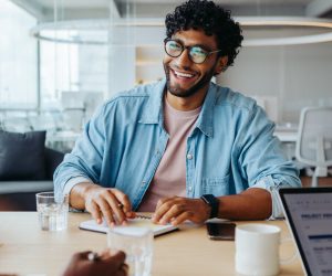 Business man working with colleagues in a modern office boardroom. They are discussing business ideas and planning a project together. The atmosphere is positive and everyone is engaged and smiling.