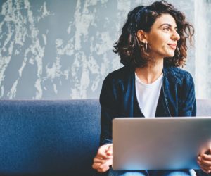 Woman with a laptop on her lap contemplating on a decision