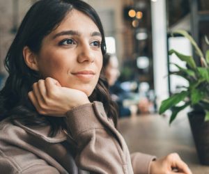 Young woman sitting in cafe and in deep thought
