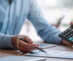 Businessman pointing graph and using calculator during a busines